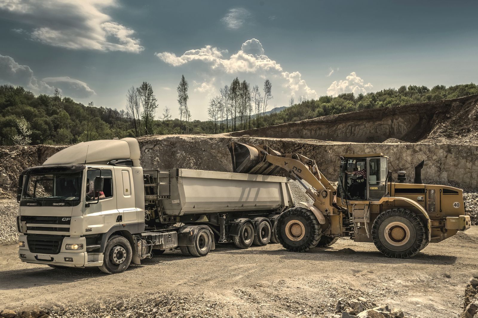 Tipper truck loaded by a wheel loader at a quarry